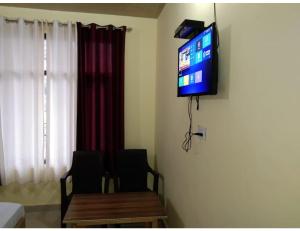 a television hanging on a wall in a room at Pine Wood Resort, Barkot in Barkot