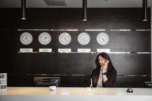 a woman talking on a cell phone in a room with clocks at The Diamond Hotel Baku in Baku