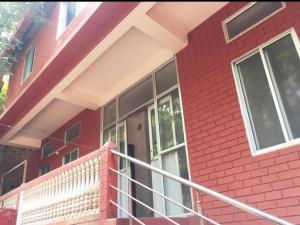 a red brick building with a balcony and a door at Hilltop Lodge in Guwahati