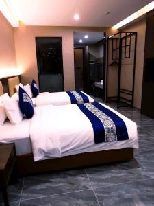 东方酒店 في سيهانوكفيل: غرفة نوم بسريرين ذات شراشف زرقاء وبيضاء