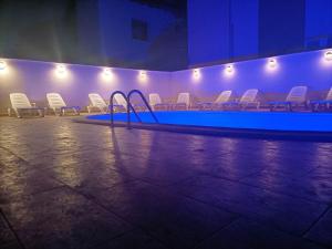 a swimming pool with white chairs in a room at Tiny Village Mamaia Nord - House 1 in Mamaia Sat/Năvodari