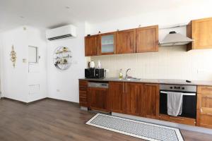 a kitchen with wooden cabinets and a stove top oven at Rothschild Allenby Penthouse 2BD in Tel Aviv