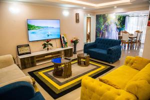 a living room with a yellow couch and a tv at The Fancy Luxurious 3 bedroom apartment in Nakuru