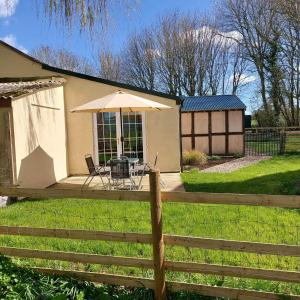 a house with a table with an umbrella and a fence at Beautiful 1-Bed Lodge in Clifford Hereford in Hereford