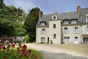 une vieille maison avec des fleurs devant elle dans l'établissement Logis Manoir De La Giraudière, à Beaumont-en-Véron