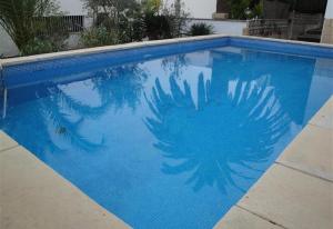 una piscina azul con una palmera reflejada en ella en Villa besides the sea - 3 bedrooms, en Tarragona