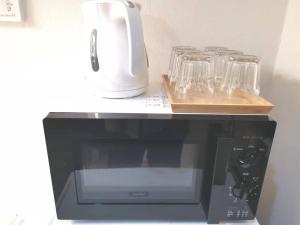 a black microwave oven with glasses on a shelf at GRHOUSE -Self Check in- Will send room number and password in Tokyo
