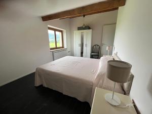 een slaapkamer met een wit bed en een tafel met een lamp bij trilocale notte nel loft di Lori 3 camere 1 bagno in Gubbio