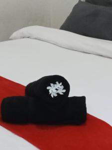 een zwarte hoed met een bloem op een bed bij MURAI Guesthouse Bali in Denpasar