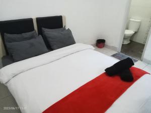 een bed met een rode en witte deken erop bij MURAI Guesthouse Bali in Denpasar