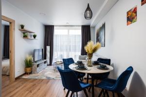 a living room with a table and blue chairs at Lazdyneliu Vingis in Vilnius