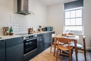 a kitchen with black cabinets and a table with chairs at Principality View Apartment Two, by Solace Stays in Cardiff