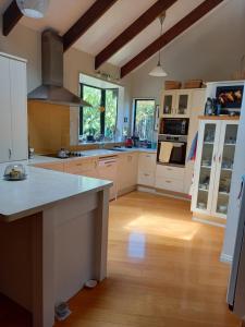 uma grande cozinha com armários brancos e uma bancada em Birds Eyes Te Awanga em Te Awanga