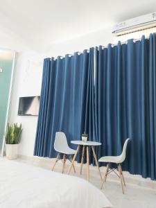 zwei Stühle und ein Tisch vor blauen Vorhängen in der Unterkunft Min homestay 5 in Buôn Ðũng