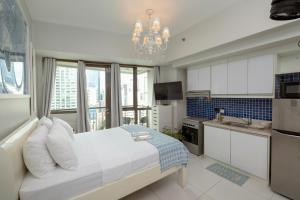 a bedroom with a bed and a kitchen with a chandelier at KL Tower Makati Apartments by PH Staycation in Manila