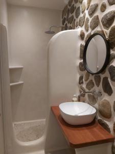 a bathroom with a sink and a mirror on a stone wall at Anna Studios in Agios Prokopios