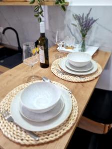 a wooden table with white plates and wine glasses at Vila Damir in Gradac