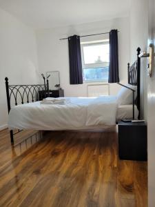 um quarto com uma cama grande e piso em madeira em Stunning 1 bedroom apartment in London em Londres