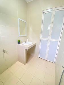 La salle de bains blanche est pourvue d'un lavabo et d'un miroir. dans l'établissement Sun Tree Hotel, à Kampong Kerayong