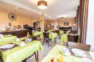 un restaurante con mesas verdes, sillas y una barra en Hôtel De La Plage, en Le Chambon-sur-Lignon