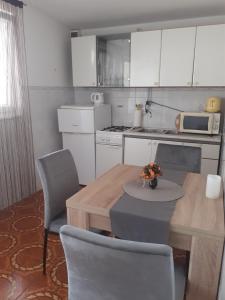 eine Küche mit einem Holztisch mit Stühlen und einer Tableasteryasteryasteryastery in der Unterkunft Apartman Čigir in Vir