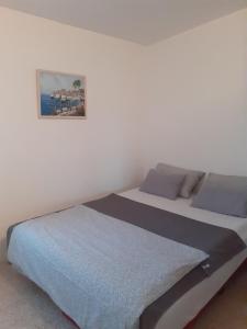 ein weißes Schlafzimmer mit einem Bett mit einem Bild an der Wand in der Unterkunft Apartman Čigir in Vir