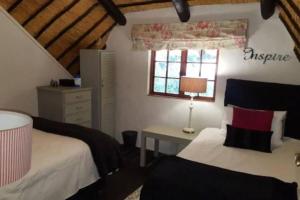 1 dormitorio con 2 camas, escritorio y ventana en The Underberg Cottage, en Underberg