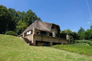 ein Haus auf einem Grashügel in der Unterkunft The Underberg Cottage in Underberg