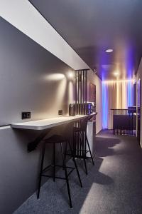 un bar con taburetes en una habitación con luces moradas en Ultramarinn Hotel, en Odessa