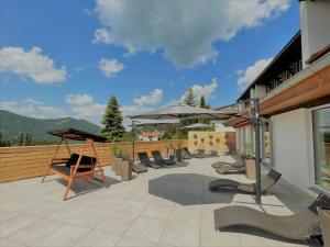 eine Terrasse mit einem Haufen Stühle und Sonnenschirme in der Unterkunft Berghoteltirol in Jungholz