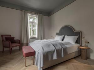 um quarto com uma cama, uma cadeira e uma janela em Villa Helvetia em Merano