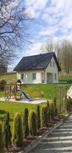 uma casa com um parque infantil no quintal em Róża Sudetów Domek em Duszniki Zdrój