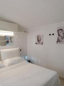 um quarto branco com uma cama e duas fotografias na parede em Romantica mansardina in centro città em Pescara
