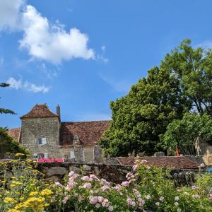 ein altes Steinhaus mit Blumen im Vordergrund in der Unterkunft Les Pierres Lotoises- le cottage in Reilhaguet