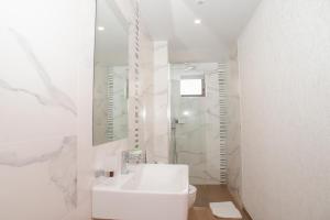 a white bathroom with a sink and a toilet at Hotel Saranda International in Sarandë