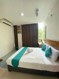 a bedroom with a large bed with green and white pillows at Sun Tree Hotel in Kampong Kerayong