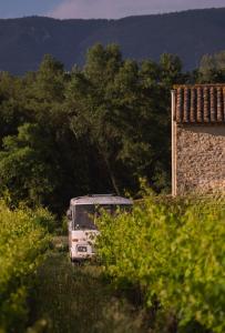una furgoneta blanca estacionada en un campo al lado de un edificio en Nuit insolite au milieu des vignes, en Goult