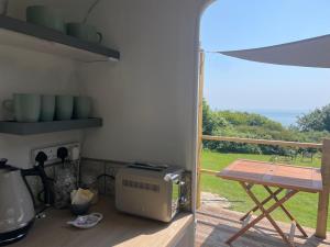 a kitchen with a microwave and a table and a balcony at Puckaster Cove Garden Yurt in Niton