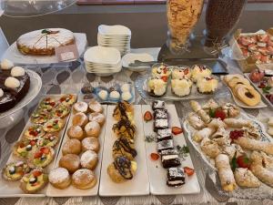 une table remplie de différents types de pâtisseries et de gâteaux dans l'établissement Hotel Villa Paola, à Rimini