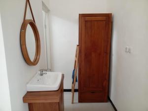 a bathroom with a sink and a mirror and a door at Cahaya 1 Guest House in Songgoriti
