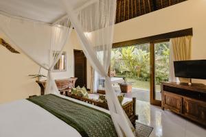 a bedroom with a bed and a tv and a window at Teja Lokha Ubud Villa in Ubud