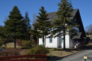 a white house with trees in front of it at Ferienwohnung Sonnenblume in Hohegeiß