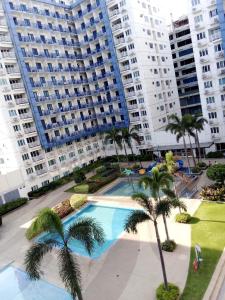 ein Pool mit Palmen vor hohen Gebäuden in der Unterkunft Sea residence reyplace in Manila