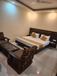 a bedroom with a large bed and a chair at Hotel City Lite Near IGI Airport Delhi in New Delhi