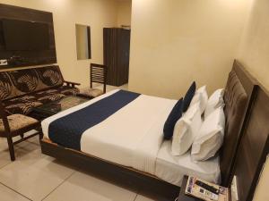 a bedroom with a bed and a chair and a television at Hotel City Lite Near IGI Airport Delhi in New Delhi