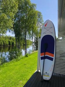 a surfboard sitting on a deck next to a river at Arctic Resort Delight in Rovaniemi