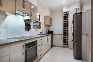 a kitchen with white cabinets and a black refrigerator at West Beach House 4U in Henley Beach South
