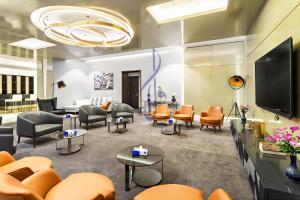 una sala de espera con sillas naranjas y TV en Walaa Homes-Luxury 2 Bedroom at DAMAC Exclusiva Tower Riyadh Saudia-3004, en Riad