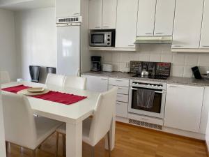 uma cozinha branca com uma mesa branca e electrodomésticos brancos em Sea, Sauna and City Center em Helsinque