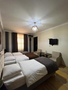 a bedroom with three beds and a flat screen tv at Issam Hotel & Spa Sheki in Sheki
